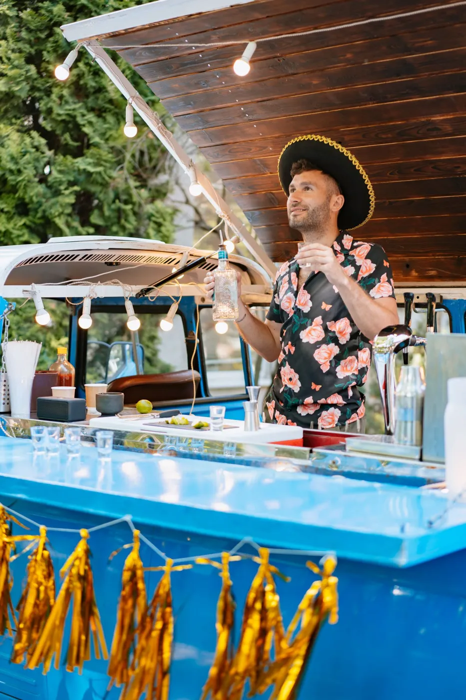 Bartender mixing drinks at an outdoor mobile cocktail bar